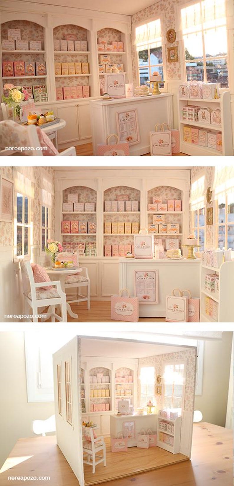 K&ouml;nnte beinhalten: Ein Miniatur-Puppenhaus-B&auml;ckereiladen mit wei&szlig;en Regalen voller kleiner Schachteln, einer Verkaufstheke mit Einkaufst&uuml;ten mit der Aufschrift Cake & Clover, einem kleinen Tisch mit St&uuml;hlen, gebl&uuml;mter Tapete und Fenstern mit einfallendem Tageslicht.