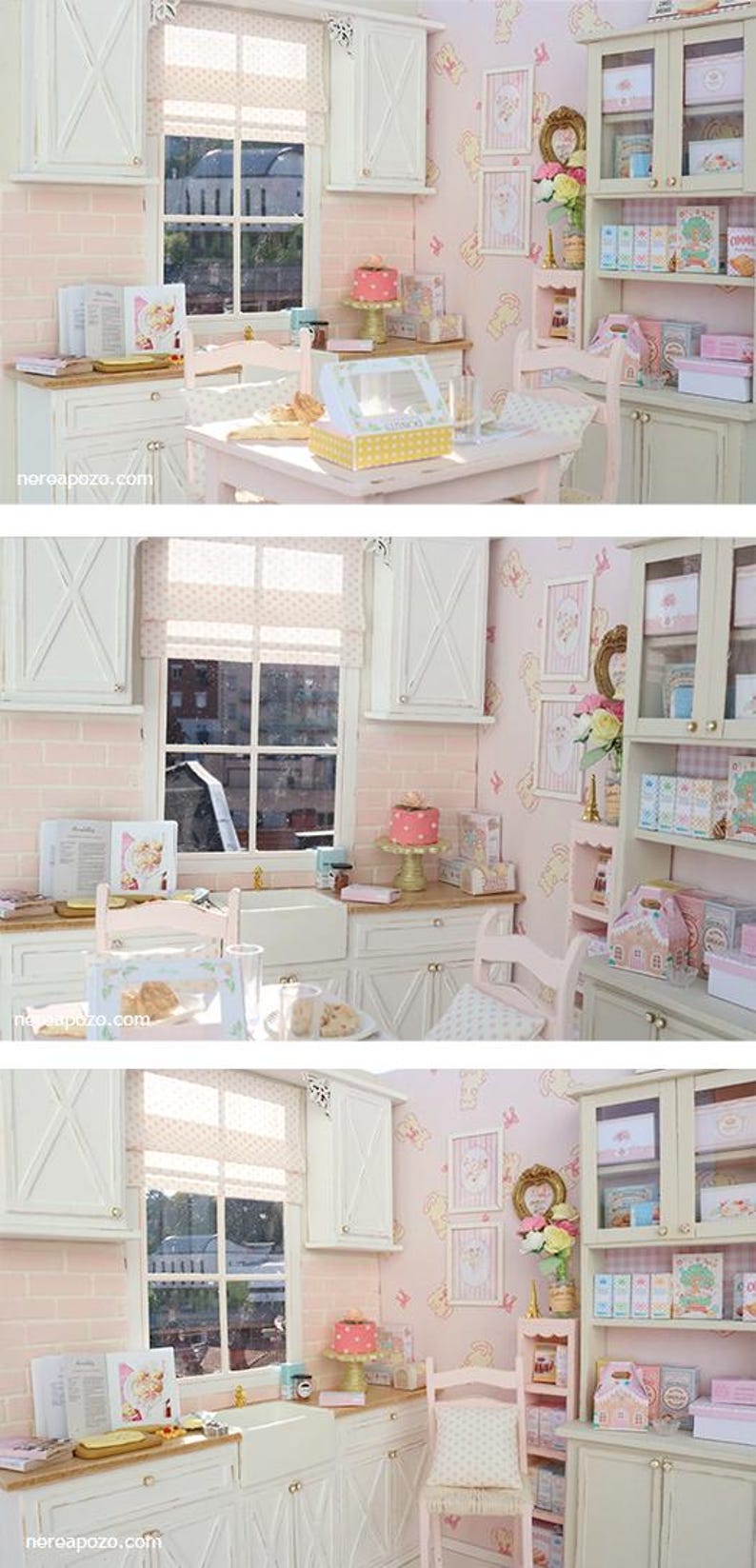 May include: A miniature kitchen scene in pink and white. The scene features a table, chairs, cabinets, and a window. A cake, boxes, and other items are on display. The walls are pink with a repeating pattern.