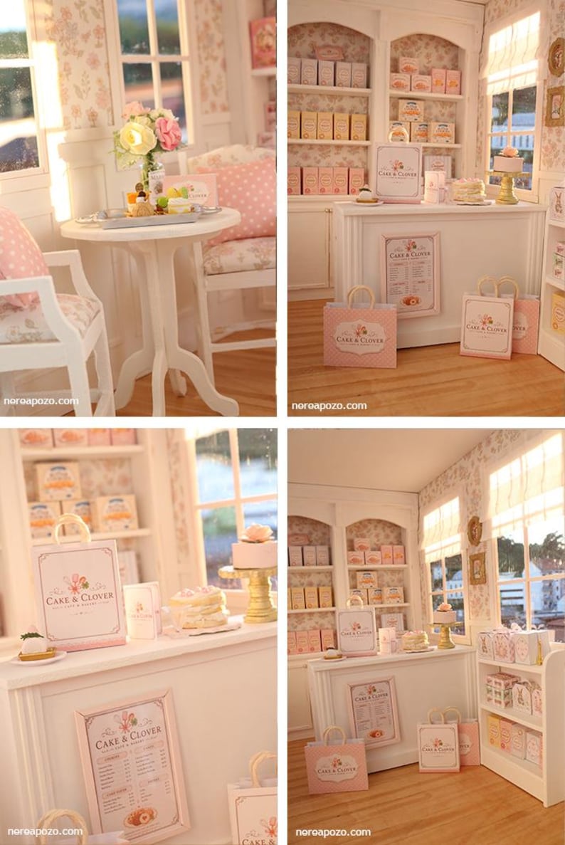 K&ouml;nnte beinhalten: Eine Miniatur-B&auml;ckerei mit wei&szlig;er Theke, Regalen voller Schachteln, einem Tisch mit St&uuml;hlen und Einkaufst&uuml;ten mit der Aufschrift Cake & Clover. Die Einrichtung umfasst florale Tapeten, eine Men&uuml;tafel und kleine Kuchen in einer Puppenstube.