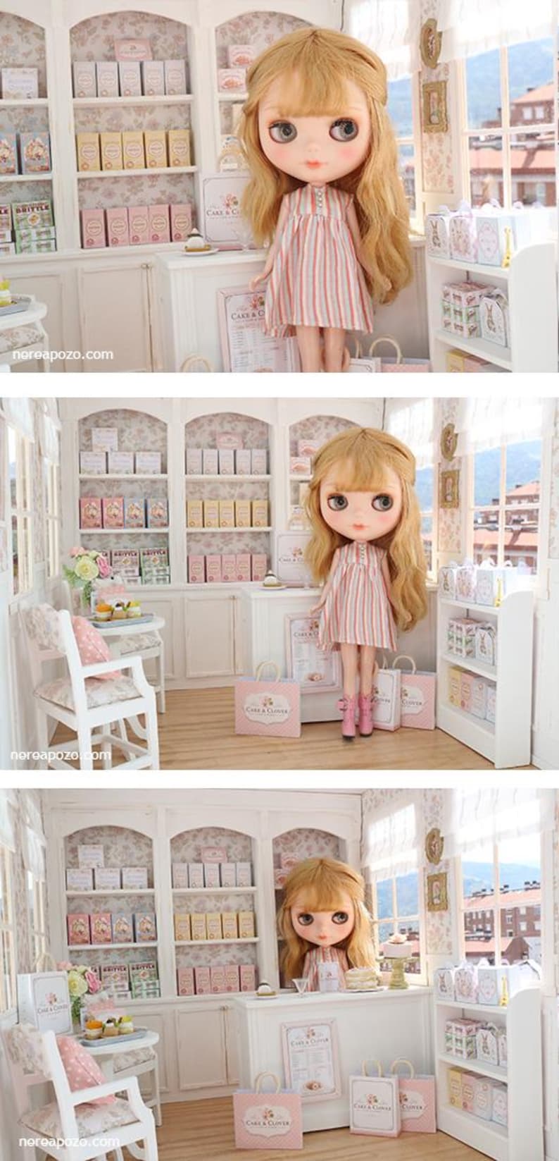 K&ouml;nnte beinhalten: Eine blonde Puppe mit gro&szlig;en Augen tr&auml;gt ein &auml;rmelloses Kleid mit vertikalen rosa, blauen und wei&szlig;en Streifen sowie rosa Stiefel und steht in einer Miniatur-B&auml;ckerei mit wei&szlig;en Regalen, pastellfarbenen Schachteln und Einkaufst&uuml;ten mit der Aufschrift Cake & Clover.