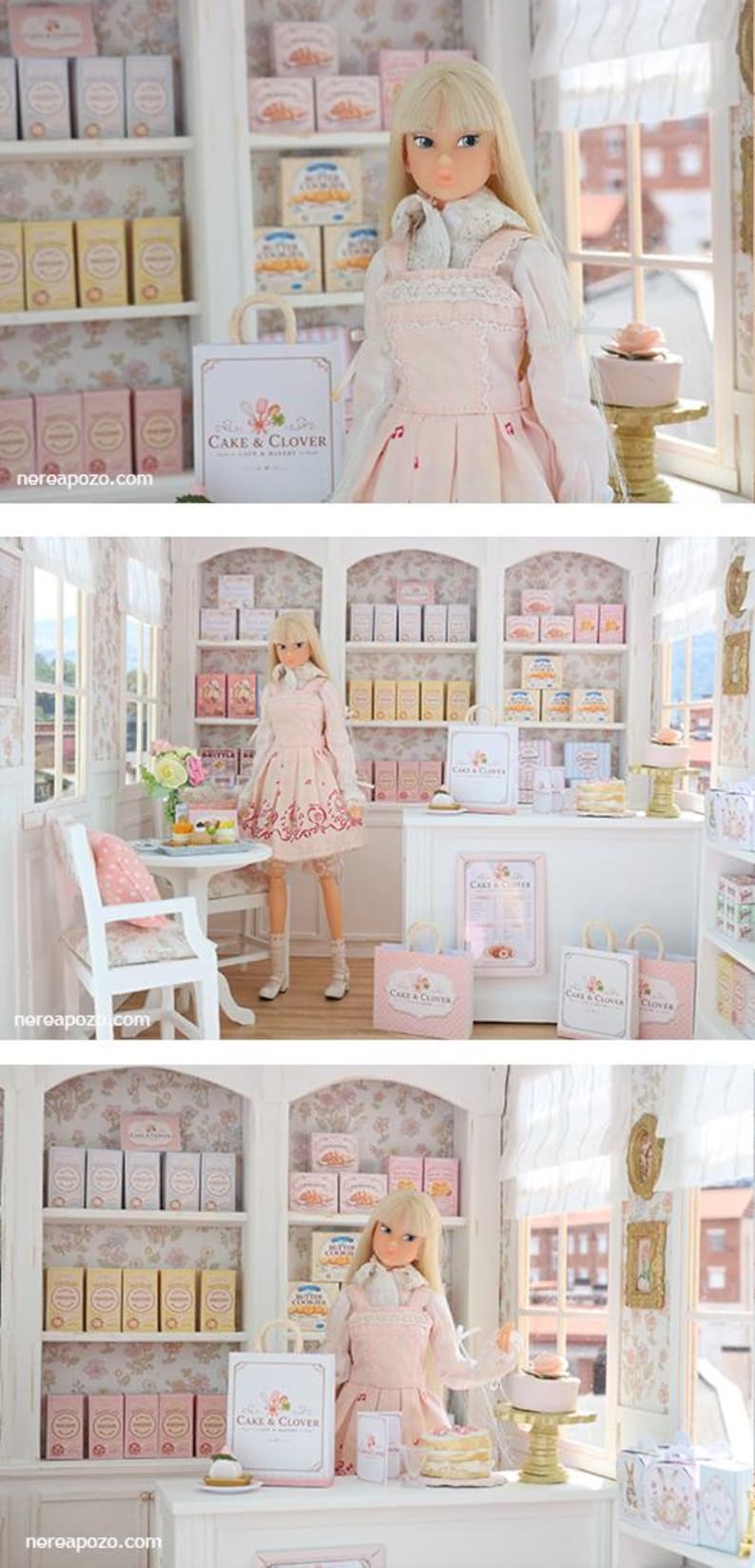 K&ouml;nnte beinhalten: Eine blonde Puppe in einem hellrosa Tr&auml;gerkleid und wei&szlig;er Bluse steht in einer Miniatur-B&auml;ckerei. Der Laden verf&uuml;gt &uuml;ber wei&szlig;e Regale mit kleinen Schachteln mit der Aufschrift Cake & Clover, eine wei&szlig;e Theke und Einkaufst&uuml;ten mit Logo.