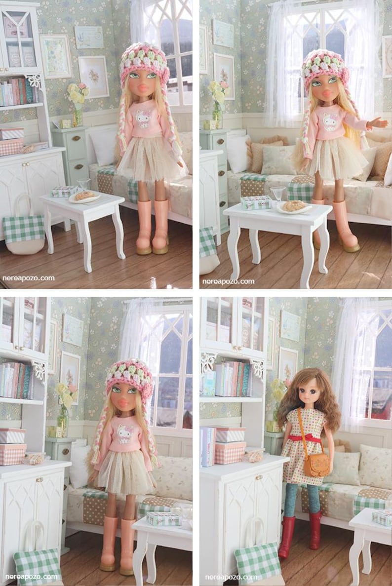 Może przedstawiać: Lalka w r&oacute;żowej bluzce z długim rękawem, beżowej sp&oacute;dnicy i r&oacute;żowych butach. Lalka ma r&oacute;żowo-zielony kapelusz z szydełka i długie blond warkocze. Lalka znajduje się w miniaturowym pokoju z białymi meblami i kwiatową tapetą.