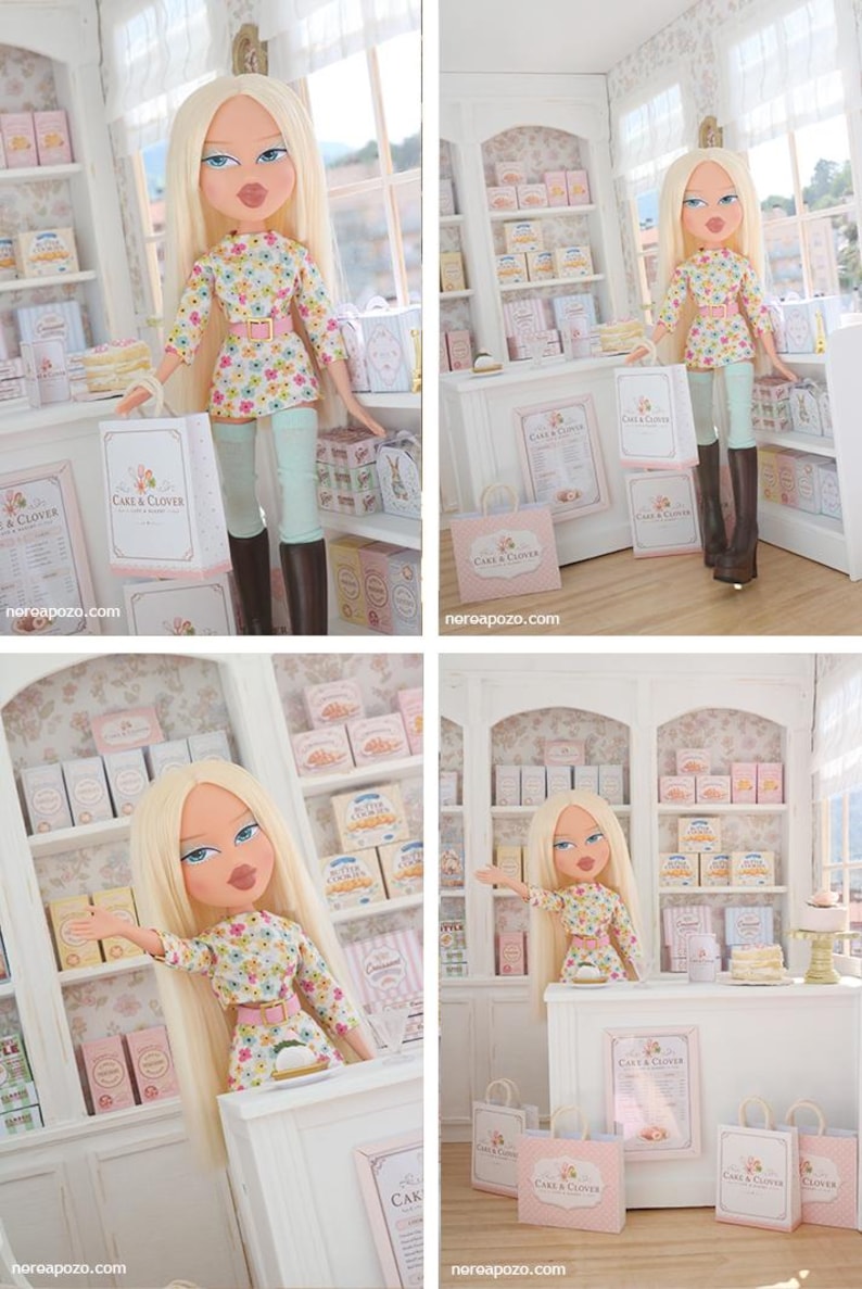 K&ouml;nnte beinhalten: Eine blonde Puppe mit blauen Augen tr&auml;gt ein lang&auml;rmeliges Blumenoberteil, einen rosa G&uuml;rtel und hellblaue Leggings mit braunen Stiefeln. Die Puppe befindet sich in einer Miniatur-B&auml;ckerei mit wei&szlig;en Regalen, rosa-wei&szlig;en Schachteln und Cake & Clover-T&uuml;ten.