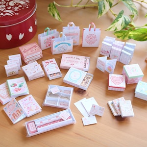 May include: A collection of miniature Valentine's Day themed gift boxes, bags, and cards. The boxes are decorated with hearts, flowers, and the words "Lovely Day Chocolate".