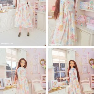 May include: A doll in a miniature kitchen, wearing a long-sleeved dress with a floral pattern. The dress has a white collar and pastel floral design. The doll has long brown hair, pink leggings, and brown boots. The setting is a miniature kitchen.
