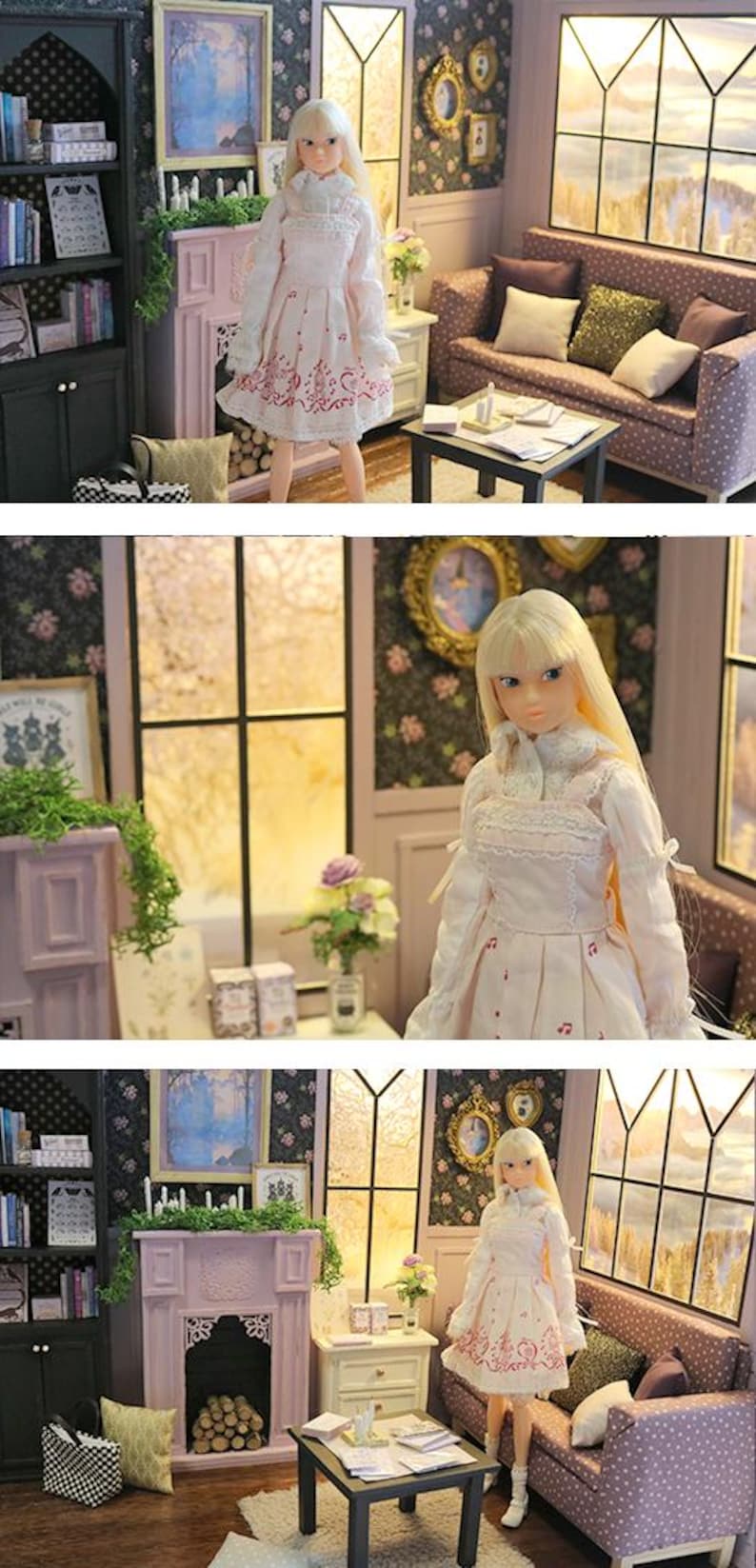 May include: A blonde doll with long hair wearing a white long-sleeved dress with a pink floral pattern on the skirt, a high collar, and lace trim. The doll stands in a miniature room setting featuring a fireplace, a sofa, and a bookshelf.