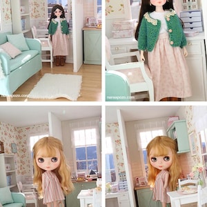 May include: A dollhouse scene with a doll in a pink dress and green jacket. The doll is in a miniature room with floral wallpaper, a sofa, and a small table. The room is decorated in pastel colours.