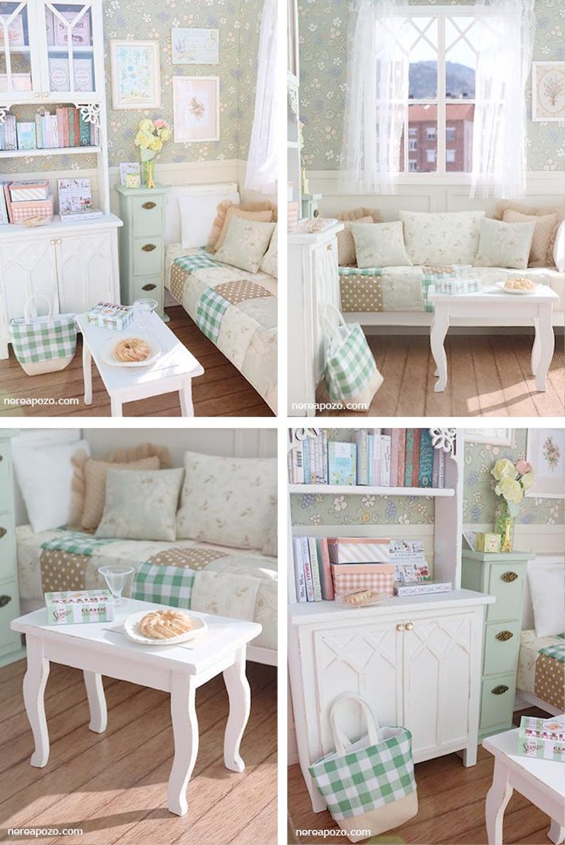 Może przedstawiać: Miniaturowe wnętrze domku dla lalek z ł&oacute;żkiem, sofą i białymi meblami. Pok&oacute;j posiada kwiatową tapetę, oprawione dzieła sztuki i mały biały stolik z talerzem ciasteczek. Widoczna jest zielono-biała torba typu tote w kratę.