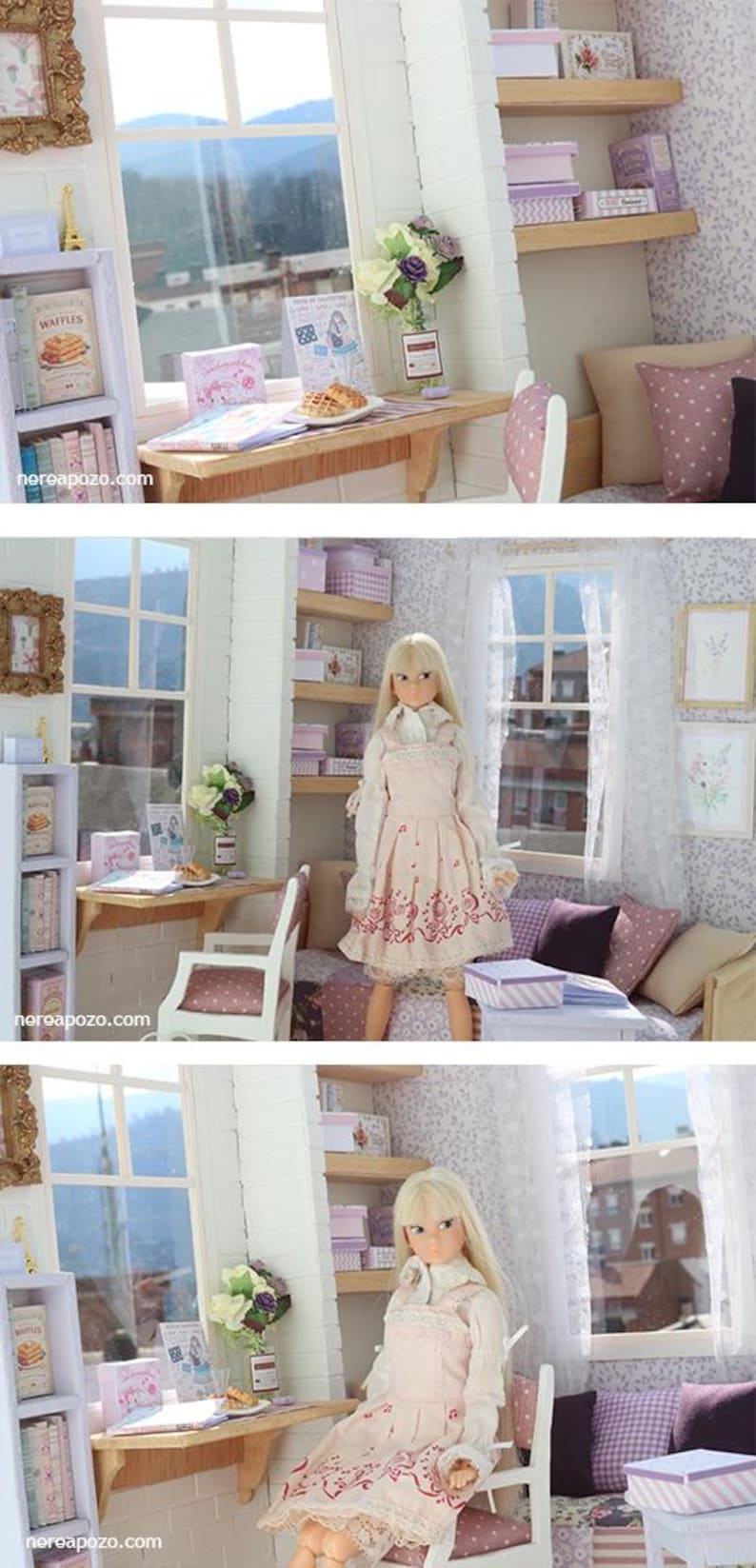 Pode incluir: Cena de casa de bonecas em miniatura com uma boneca vestida com um vestido rosa. O quarto apresenta uma mesa com uma bolacha, livros e um vaso de flores. Prateleiras com caixas e livros. Uma janela oferece uma vista de uma montanha.