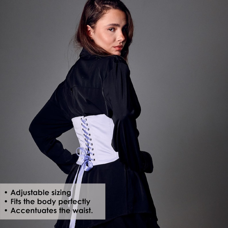 May include: A white corset with light blue lacing and ribbons. The corset is worn over a black top. The image shows the back of the corset, highlighting its adjustable sizing and waist-accentuating design.
