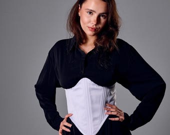 May include: A white satin corset with vertical seams is worn over a black top. The corset has a pointed bottom and a structured design. The text at the bottom reads "Custom sizes | High-quality satin".