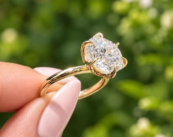 May include: A gold ring featuring a large, round, brilliant-cut clear gemstone held in place by a six-prong setting. The band is smooth and polished, showcasing a classic design that highlights the clarity and sparkle of the central stone.