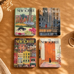 Puede incluir: Cuatro posavasos rectangulares con portadas vintage de la revista The New Yorker. Uno muestra un jardín con un gato negro, otro un puente urbano, otro una calle colorida de edificios y otro una puerta naranja con un gato negro sentado.