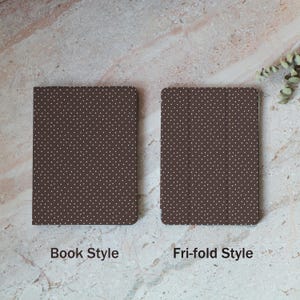 May include: Two brown cases with white polka dots are displayed. One is a book style case, and the other is a tri-fold style case. The cases are on a light brown and white marble surface. The text "Book Style" and "Tri-fold Style" are below the cases.