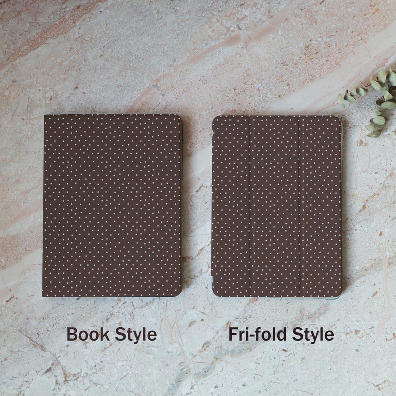 May include: Two brown cases with white polka dots are displayed. One is a book style case, and the other is a tri-fold style case. The cases are on a light brown and white marble surface. The text "Book Style" and "Tri-fold Style" are below the cases.