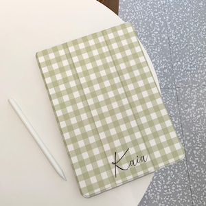 Op de afbeelding: Een groene en witte gingham iPad-hoes met de naam "Kaia" in zwarte schrijfletters.