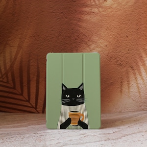 Könnte beinhalten: Eine hellgrüne Tablet-Hülle mit einer Illustration einer schwarzen Katze, die eine gelb-orange gestreifte Tasse hält. Die Katze trägt ein gestreiftes Hemd. Die Hülle hat eine Klappabdeckung.