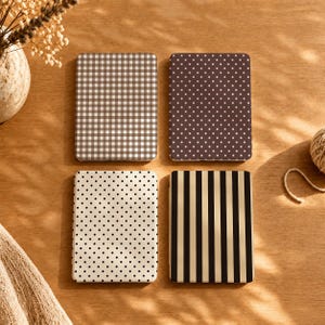 May include: Four rectangular cases with distinct patterns: one with a brown and white gingham check, one with a dark brown background featuring white polka dots, one with a cream background featuring black polka dots, and one with vertical black and beige stripes.