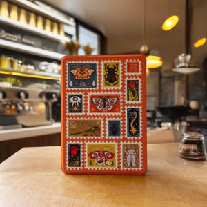 May include: An orange rectangular tin featuring a collection of postage stamp-style illustrations of insects and botanical elements. The stamps are in various colors, including blue, red, and yellow, with decorative borders. The tin is sitting on a wooden surface.