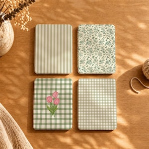 May include: Four rectangular e-reader cases arranged in a grid. One features light green vertical stripes, another a green floral and butterfly pattern, one a green and white gingham check with three pink tulips, and one a green and white gingham check.
