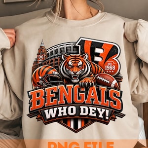 Könnte beinhalten: Ein beigefarbenes Sweatshirt mit Rundhalsausschnitt und einem Grafikdruck eines Tigers, eines Footballhelms, eines Footballs und eines Stadions. Das Design enthält den Text BENGALS, WHO DEY! und EST. 1968 in orangefarbenen und schwarzen Buchstaben.