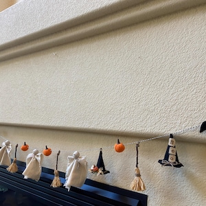 Puede incluir: Guirnalda temática de Halloween con murciélagos, sombreros de bruja, fantasmas y calabazas de fieltro. La guirnalda incluye pequeñas escobas y está colgada sobre una chimenea. Una decoración festiva para la festividad.