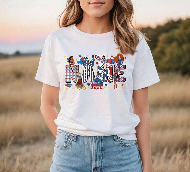 K&ouml;nnte beinhalten: Wei&szlig;es T-Shirt mit dem Wort "NAME" in einem farbenfrohen, patriotischen Design. Die Buchstaben sind mit Bildern von Frauen, Luftballons und Mustern in Rot, Wei&szlig; und Blau verziert. Das T-Shirt wird mit einer Jeans getragen.