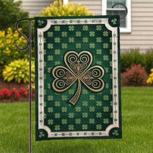 Può includere: Una bandiera da giardino verde con un design a trifoglio dorato. La bandiera ha un bordo bianco con un motivo a trifoglio ripetuto ed è esposta su un supporto in metallo nero. Il trifoglio è un simbolo del giorno di San Patrizio.