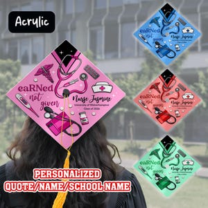May include: A personalized graduation cap with medical-themed graphics, including a stethoscope, thermometer, and caduceus. The cap is pink, with the text "eaRNed not given" and "Nurse Jasmine". The image also shows three other caps in blue, red, and green.
