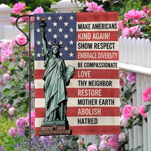 May include: A garden flag featuring the Statue of Liberty against a backdrop of the American flag. The flag includes the text: "MAKE AMERICANS KIND AGAIN! SHOW RESPECT, EMBRACE DIVERSITY, BE COMPASSIONATE, LOVE, THY NEIGHBOR, RESTORE MOTHER EARTH, ABOLISH HATRED."
