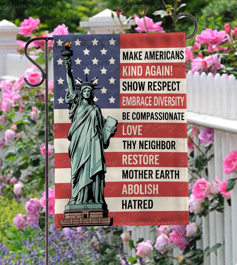 May include: A garden flag featuring the Statue of Liberty against a backdrop of the American flag. The flag includes the text: "MAKE AMERICANS KIND AGAIN! SHOW RESPECT, EMBRACE DIVERSITY, BE COMPASSIONATE, LOVE, THY NEIGHBOR, RESTORE MOTHER EARTH, ABOLISH HATRED."