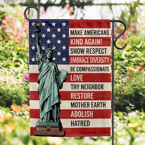 May include: A garden flag featuring the Statue of Liberty against a backdrop of the American flag. The flag includes the text: "MAKE AMERICANS KIND AGAIN! SHOW RESPECT, EMBRACE DIVERSITY, BE COMPASSIONATE, LOVE, THY NEIGHBOR, RESTORE MOTHER EARTH, ABOLISH HATRED."
