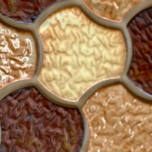 Pode incluir: Close-up de um padr&atilde;o de ladrilhos texturizados com uma mistura de cores marrom, bege e creme. Os ladrilhos s&atilde;o dispostos em um padr&atilde;o de favo de mel.