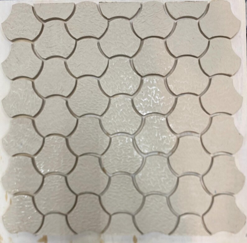 Pode incluir: Uma folha de azulejos de cer&acirc;mica branca com um padr&atilde;o em forma de leque. Os azulejos s&atilde;o dispostos em um padr&atilde;o repetitivo.