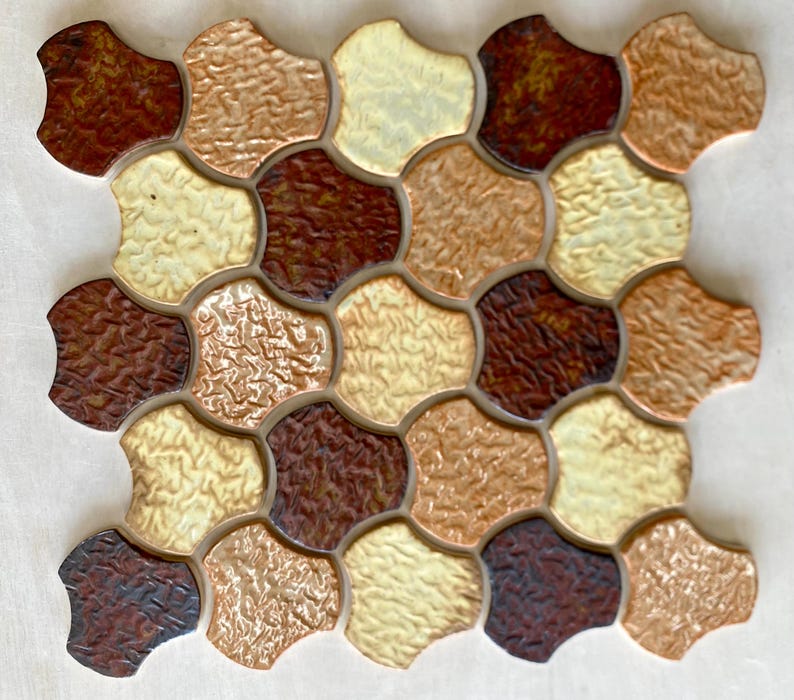 Pode incluir: Uma folha de azulejos de cer&acirc;mica marrom, bege e creme com uma superf&iacute;cie texturizada. Os azulejos t&ecirc;m a forma de hex&aacute;gonos arredondados e est&atilde;o dispostos em um padr&atilde;o repetitivo.