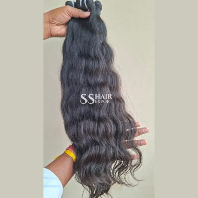 Pu&ograve; includere: Extension di capelli ondulati scuri, tenute contro uno sfondo neutro. I capelli sono di un colore nero profondo e naturale, con onde e ricci visibili. Il testo "SS HAIR EXPORT" &egrave; visibile sui capelli.