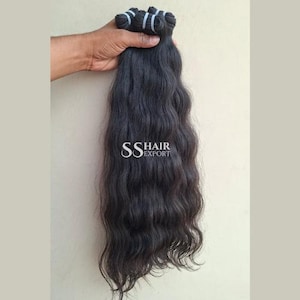 Pu&ograve; includere: Un fascio di capelli scuri e ondulati tenuto in una mano. I capelli sono di un nero intenso con onde naturali. Il testo "SS HAIR EXPORT" &egrave; visibile nell'immagine.