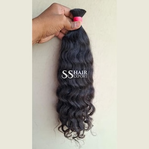 Puede incluir: Un mechón de extensiones de cabello largo, ondulado y de color marrón oscuro, asegurado en la parte superior con una banda rosa. El cabello tiene una textura natural y un ligero brillo. El texto SS HAIR EXPORT aparece en letras blancas.