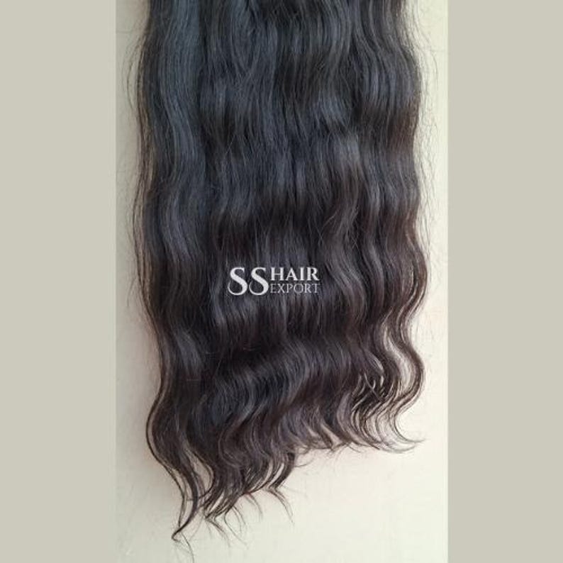 Pu&ograve; includere: Extension di capelli neri ondulati scuri. I capelli sono folti e sembrano non trattati. Il testo "SS HAIR EXPORT" &egrave; stampato sui capelli.