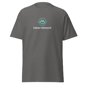 Peut inclure: Un t-shirt gris foncé avec un logo blanc représentant une forme géométrique stylisée bleue et verte. Le texte "Zebec Network" est imprimé sous le logo.
