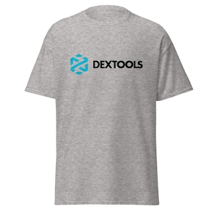May include: A heather gray t-shirt featuring the text "DEXTOOLS" in black, with a blue and white geometric logo on the left side. The shirt has short sleeves and a crew neck.