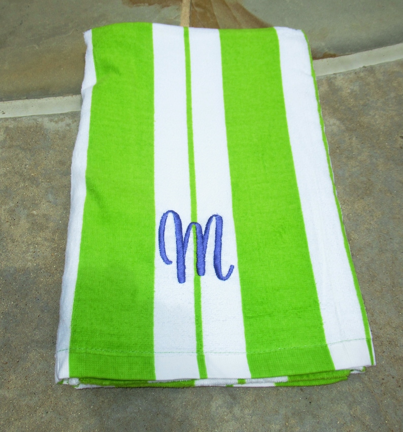 A lime green beach towel personalized in velour 100% cotton with the single initial in cursive font in purple thread.