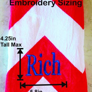 Puede incluir: Toalla de playa con estampado de chevr&oacute;n rojo y blanco con el nombre "Rich" bordado en azul. El &aacute;rea de bordado mide 10,8 cm de alto y 14,7 cm de ancho. El texto "Embroidery Sizing" est&aacute; en la parte superior.