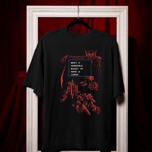 Model wearing a black relaxed fit gothic vampire graphic T-shirt with red retro pixel horror artwork.