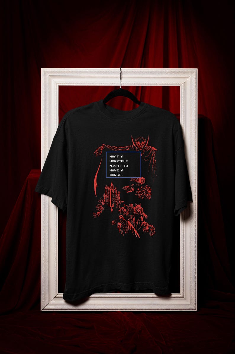Model wearing a black relaxed fit gothic vampire graphic T-shirt with red retro pixel horror artwork.