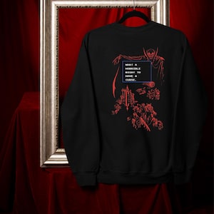 May include: Black sweatshirt with a red graphic design featuring a vampire, castle, and the text "WHAT A HORRIBLE NIGHT TO HAVE A CURSE." The design is reminiscent of a retro video game aesthetic. The sweatshirt is displayed on a hanger.