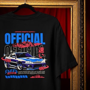 May include: Black t-shirt with a blue and white car graphic. The shirt features the text "OFFICIAL" in large blue letters, with additional text and Japanese characters. The design includes the words "SPEED HUNTER".