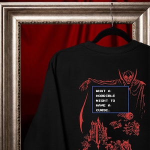 Close-up of red vampire, castle, and monster DTG print on a black Comfort Colors graphic tee.