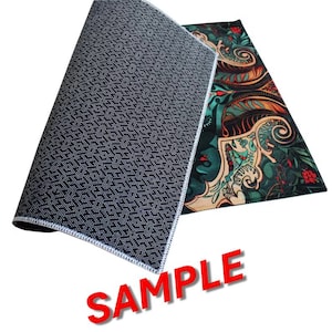 May include: A rectangular floor mat featuring a dark, intricate pattern with shades of green, orange, and red. The underside of the mat is black with a textured, non-slip geometric pattern. The word SAMPLE is printed in large red letters below.