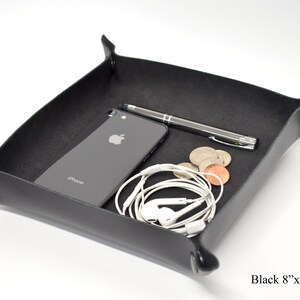 Puede incluir: Bandeja de cuero negro con esquinas redondeadas y forro de fieltro negro. La bandeja mide 20,3 cm por 20,3 cm y tiene un tel&eacute;fono, un bol&iacute;grafo y auriculares en su interior.